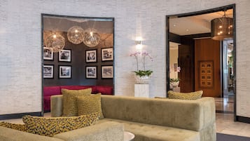 A modern living room with a sectional sofa, a red accent wall, and a series of framed photographs.
