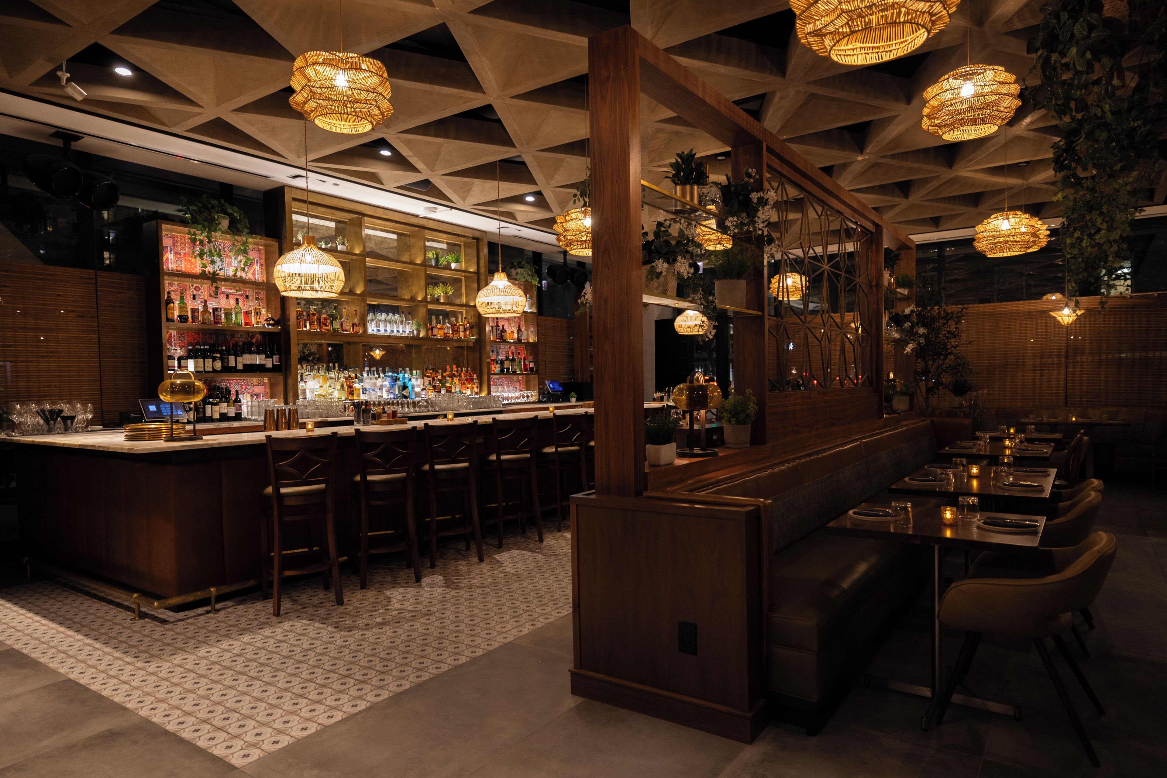 A bar area with a long counter, multiple seating options, and hanging decorative lights.