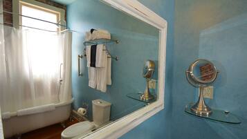 A bathroom with a bathtub, toilet, and a large mirror.