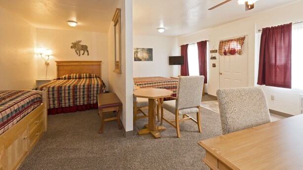 A hotel room with two beds, a dining table, a chair, a ceiling fan, and a mounted television. - All View Motel (Port Angeles)