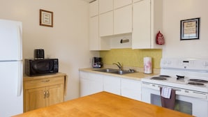 A kitchen with white cabinets, a microwave, a coffee maker, a sink, and a stove. - All View Motel (Port Angeles)