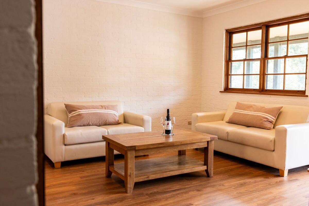 A living room with two sofas, a wooden coffee table, and a window with multiple panes.