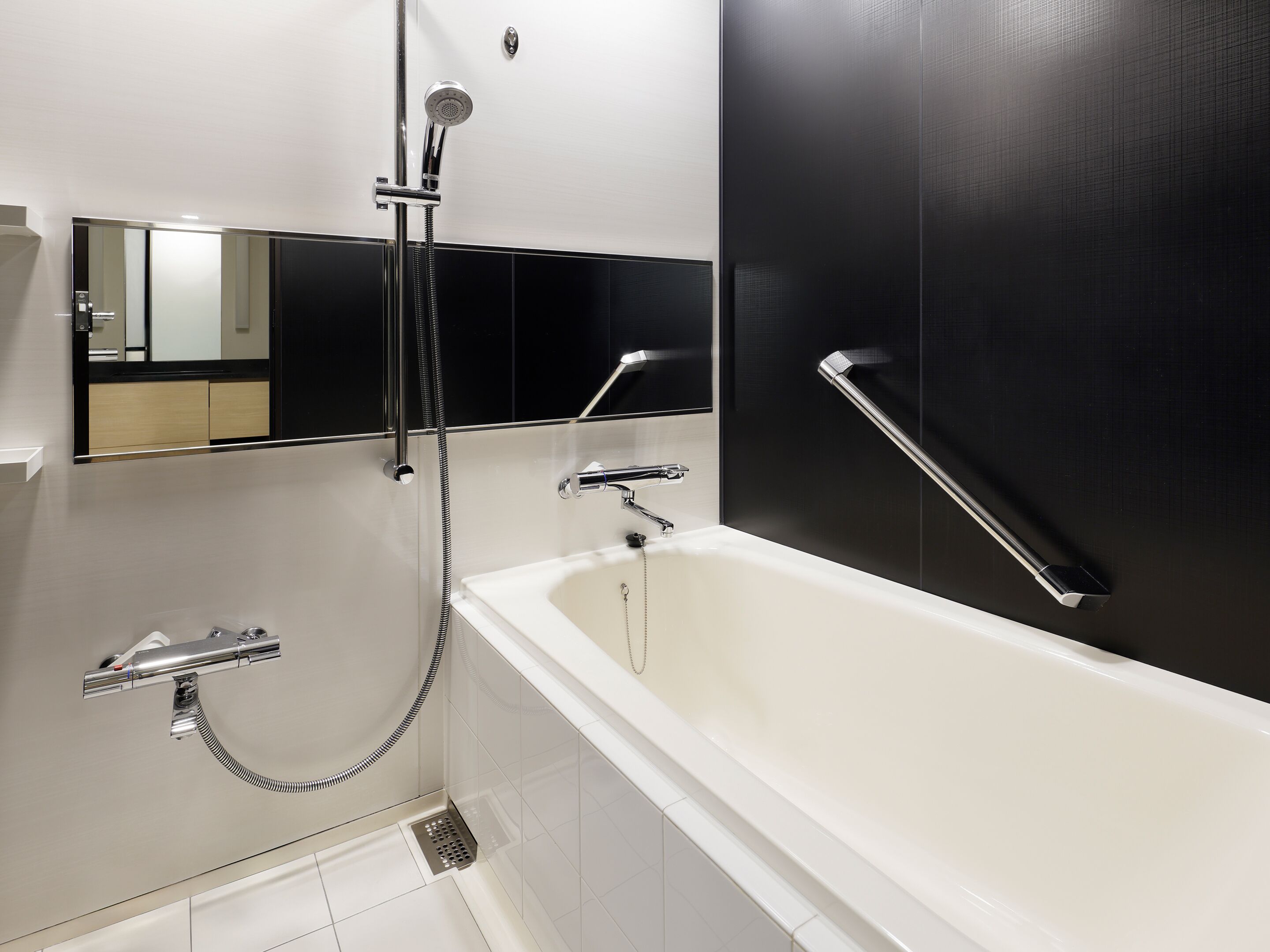 Un baño moderno con una bañera, ducha y barra de apoyo.