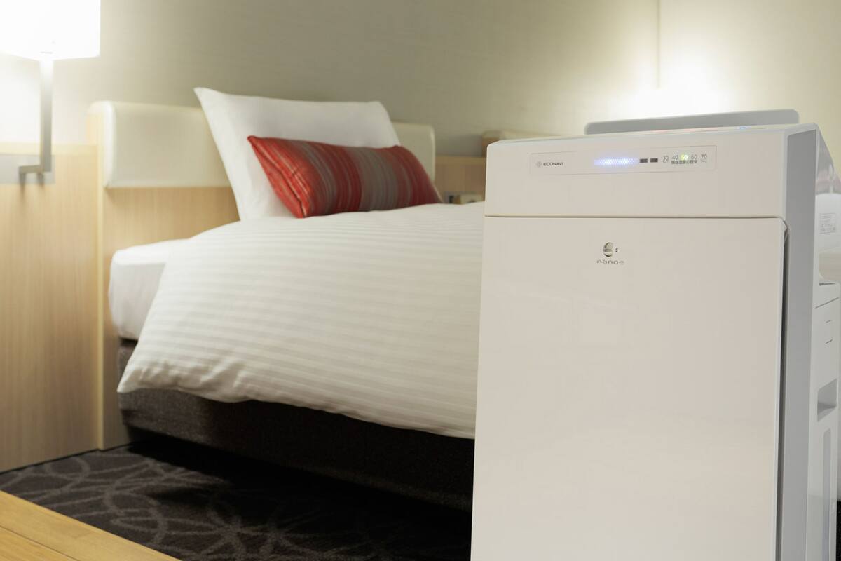 Ein Hotelzimmer mit einem Bett, einer Nachttischlampe und einem weißen Klimagerät.