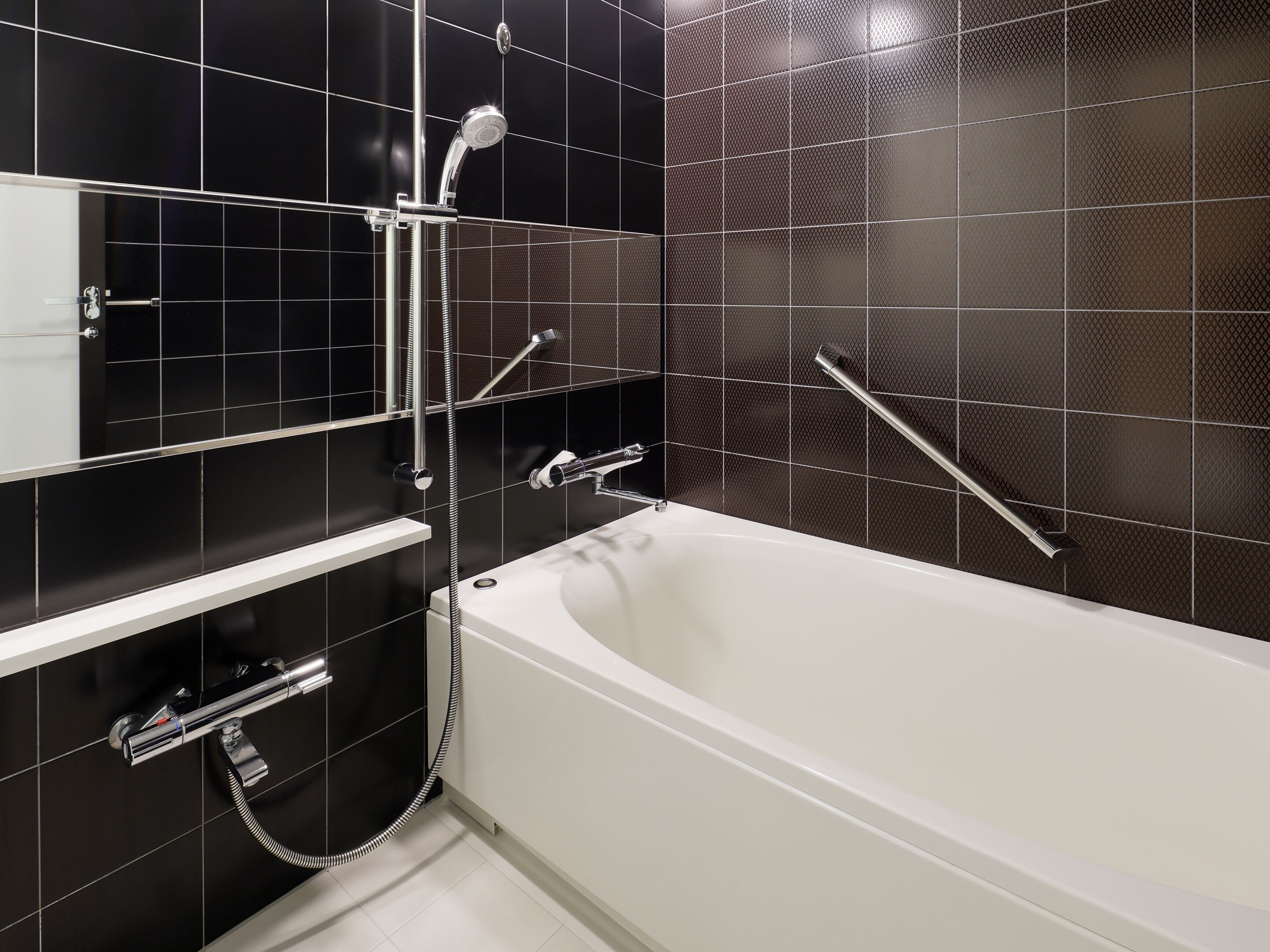 Ein modernes Badezimmer mit Badewanne, Duschkopf und Handläufe.