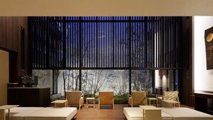 A modern interior with a seating area, a wooden floor, and a view through large windows.