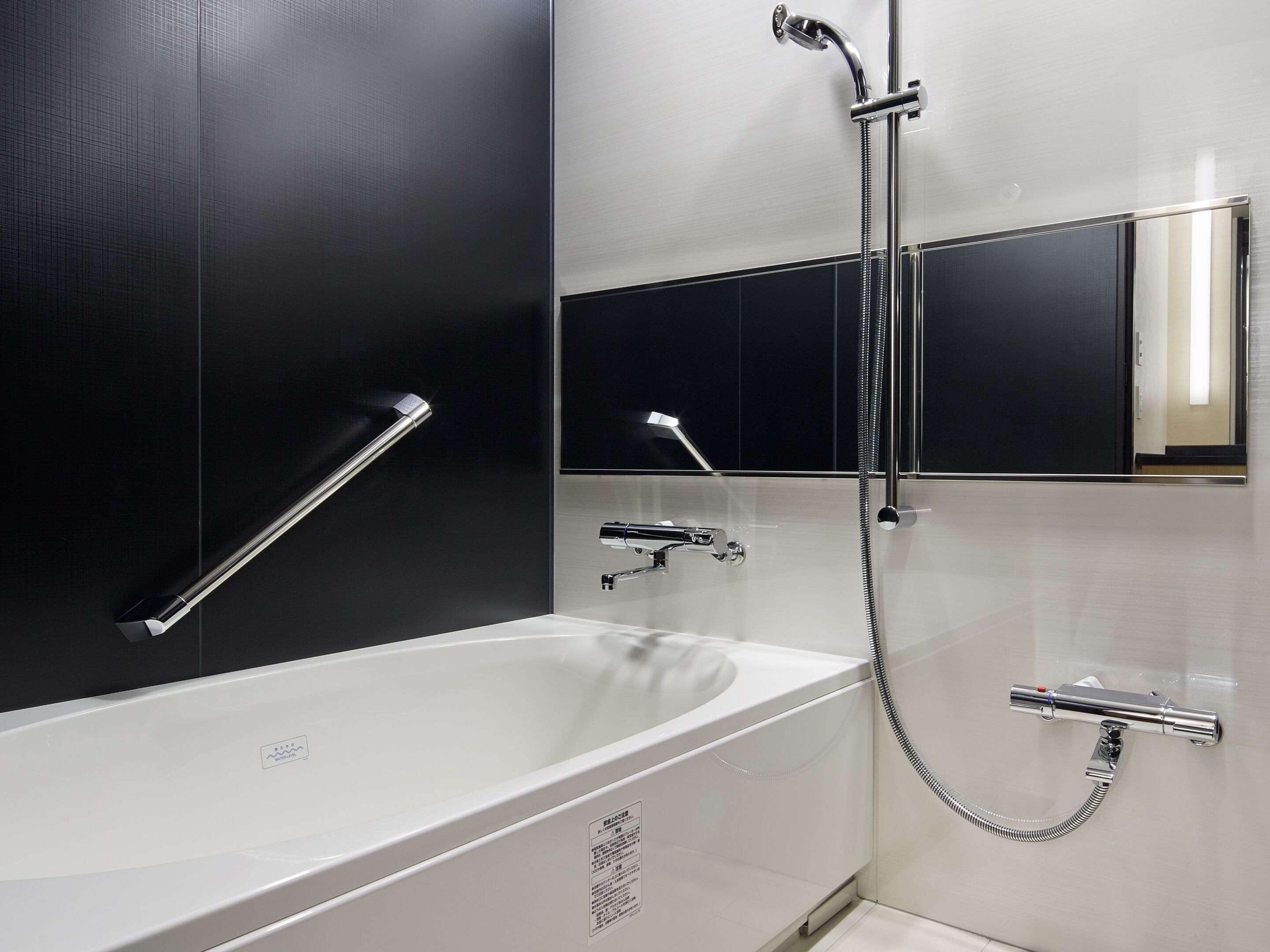 A modern bathroom with a white bathtub, a handheld showerhead, and a wall-mounted faucet.