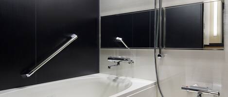 A modern bathroom with a white bathtub, a handheld showerhead, and a wall-mounted faucet.