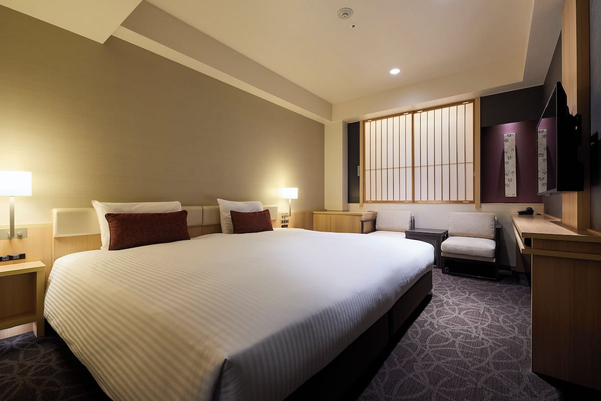 Ein Hotelzimmer mit einem großen Bett, Nachttischen, einem Schreibtisch und einem Sessel.