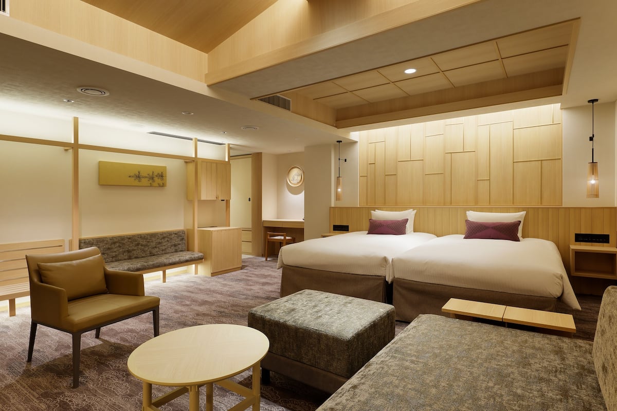 Ein Hotelzimmer mit einem großen Bett, einer Schlafcouch, einem kleinen Tisch und einem Schreibtisch.