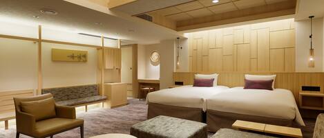 A hotel room with a large bed, a sofa, a small table, and a desk.