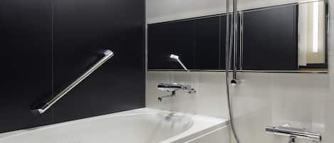 Een moderne badkamer met een bad, douche, handgreep en spiegel.