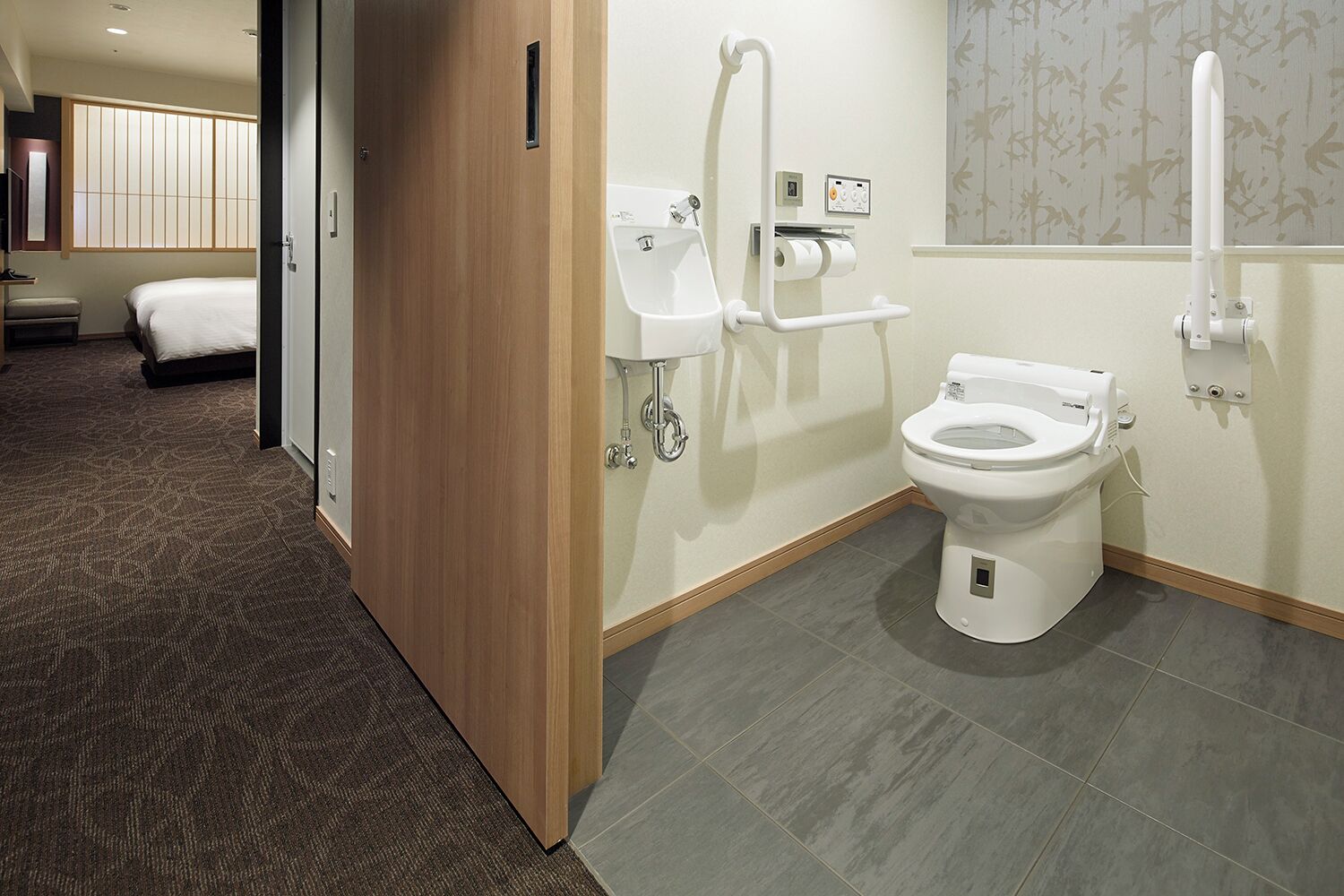 Une salle de bain d’hôtel équipée de toilettes, d’un bidet et de barres d’appui.