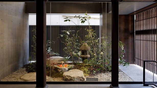 A traditional Japanese garden with a rock arrangement, a stone lantern, and bamboo plants.