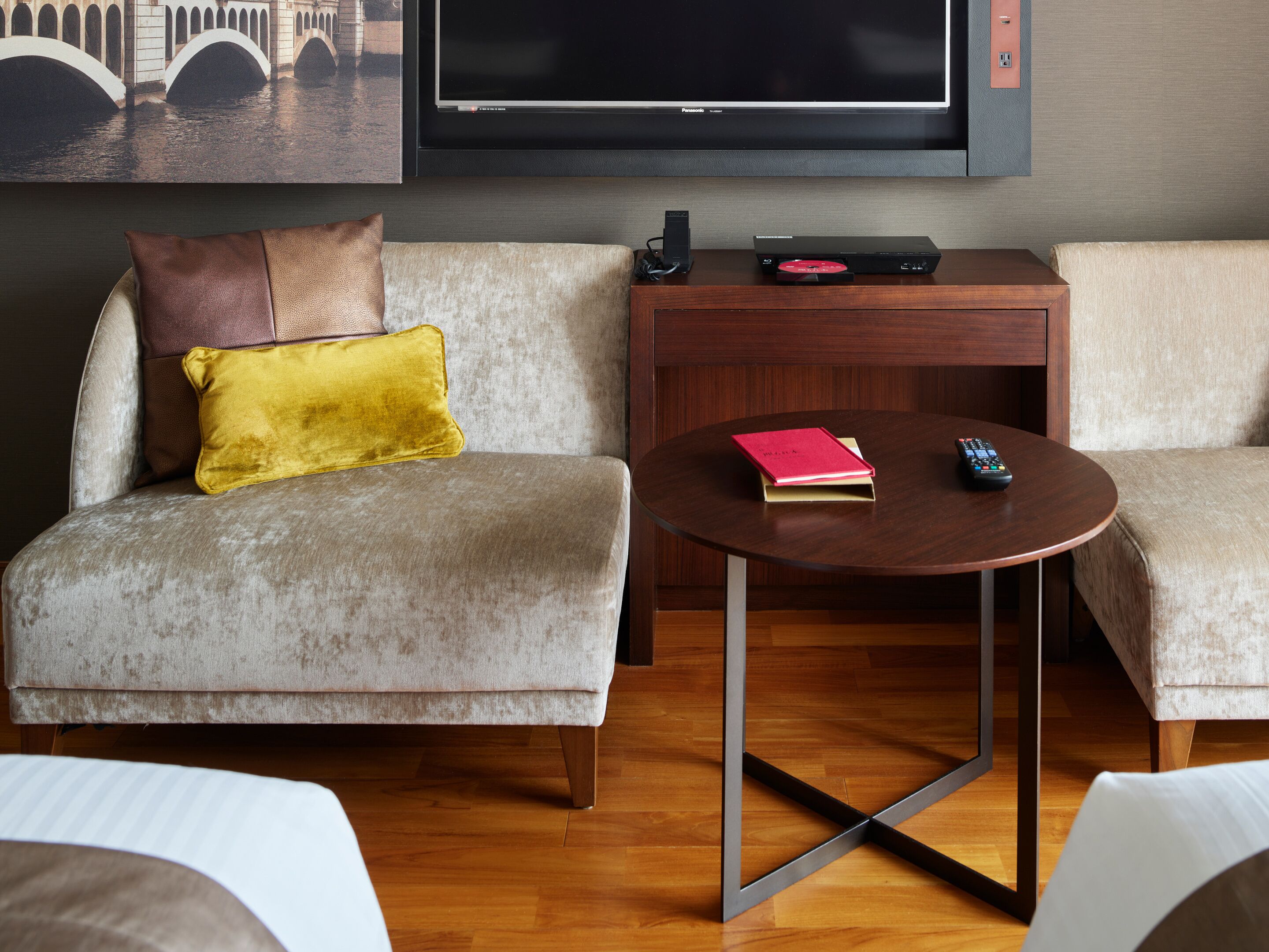 A modern living room with a sofa, a coffee table, and a flat-screen TV mounted on the wall.