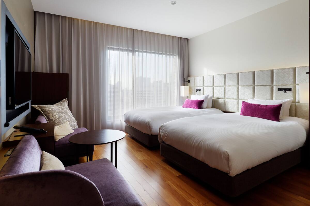 Une chambre d’hôtel avec deux lits, un canapé, une télévision et une petite table.