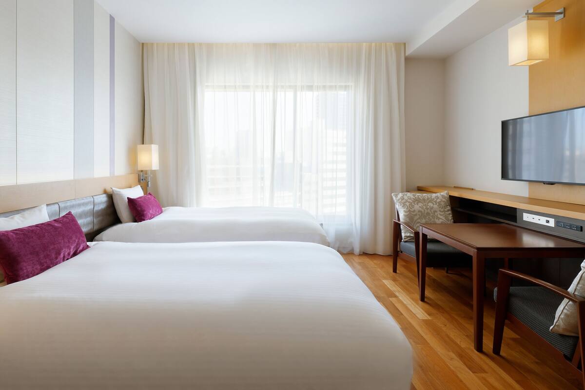 Une chambre d’hôtel avec deux lits, une télévision, un bureau et une chaise.