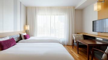 A hotel room with two beds, a TV, a desk, and a chair.