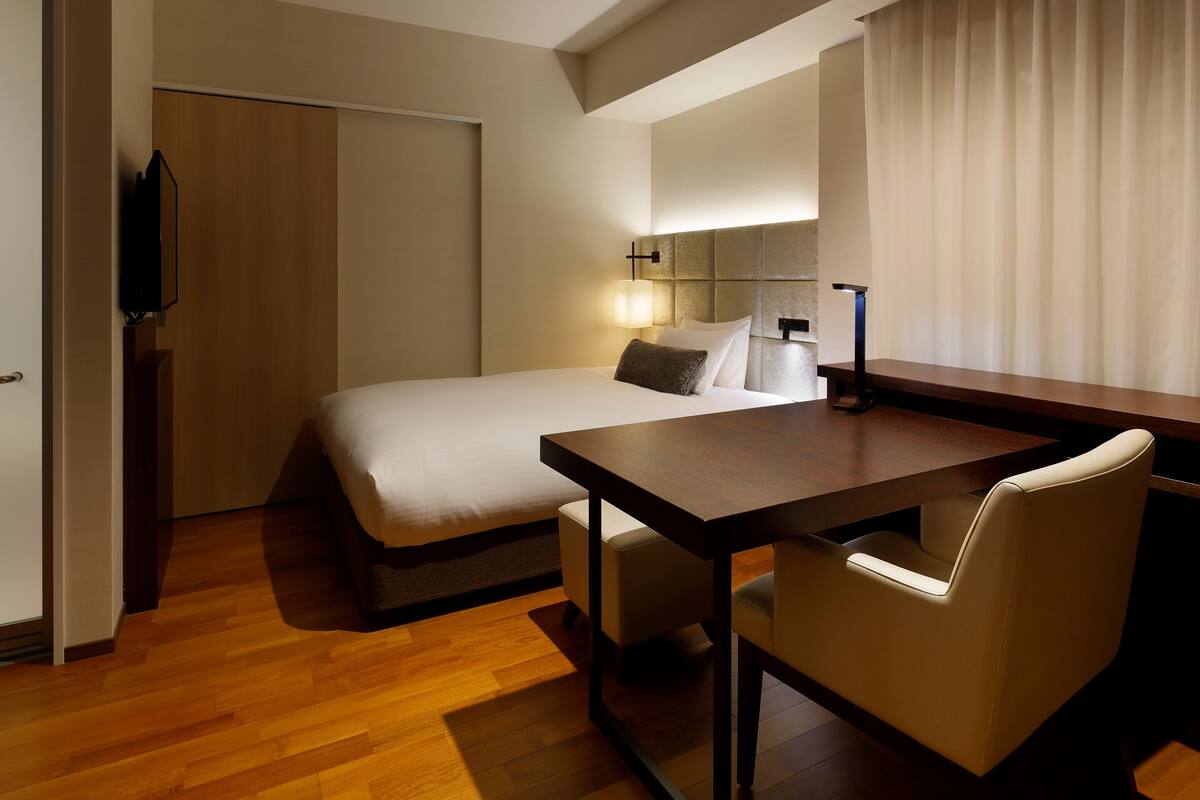 Une chambre d’hôtel comprenant un lit, une table de chevet, une chaise et un téléviseur.