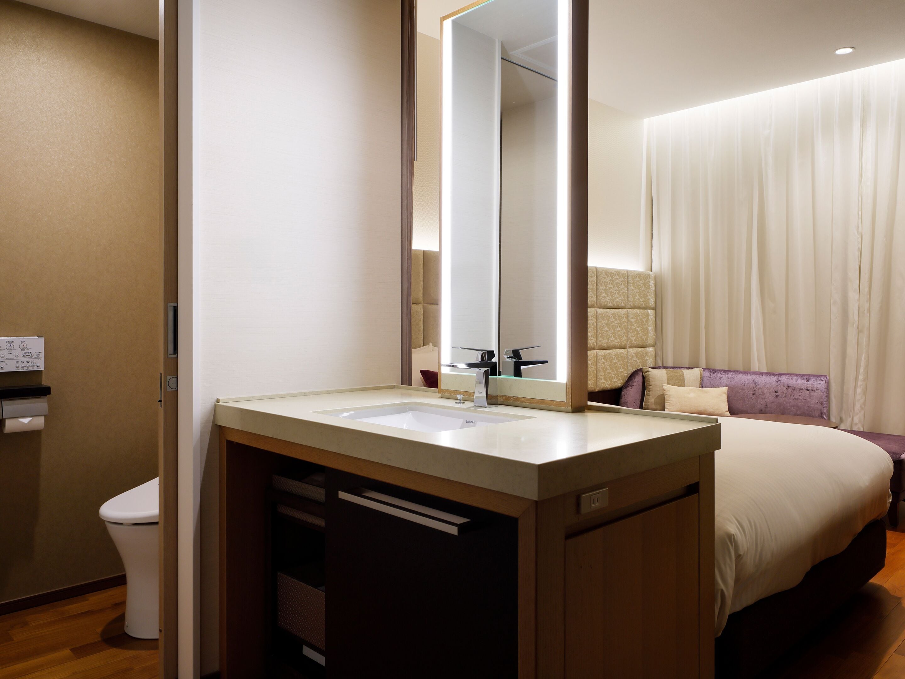 A hotel bathroom with a sink, mirror, and toilet.