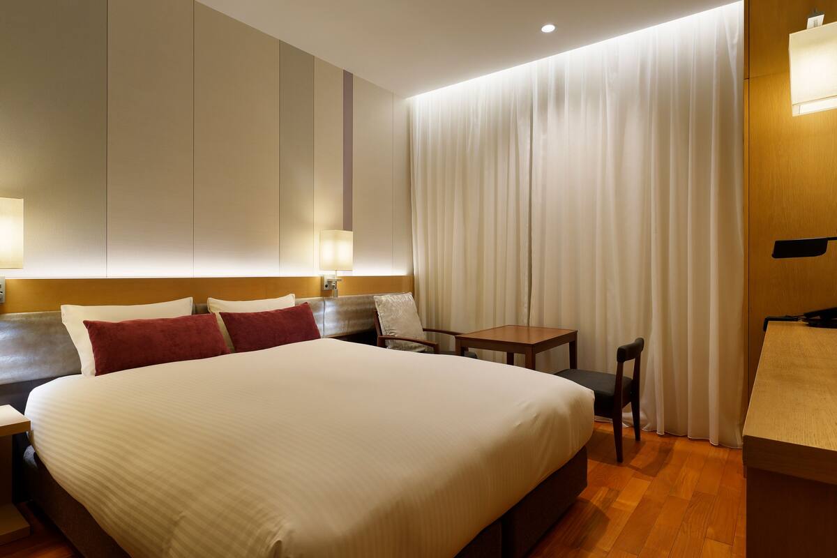 Une chambre d’hôtel avec un grand lit, des tables de chevet, un bureau et une chaise.