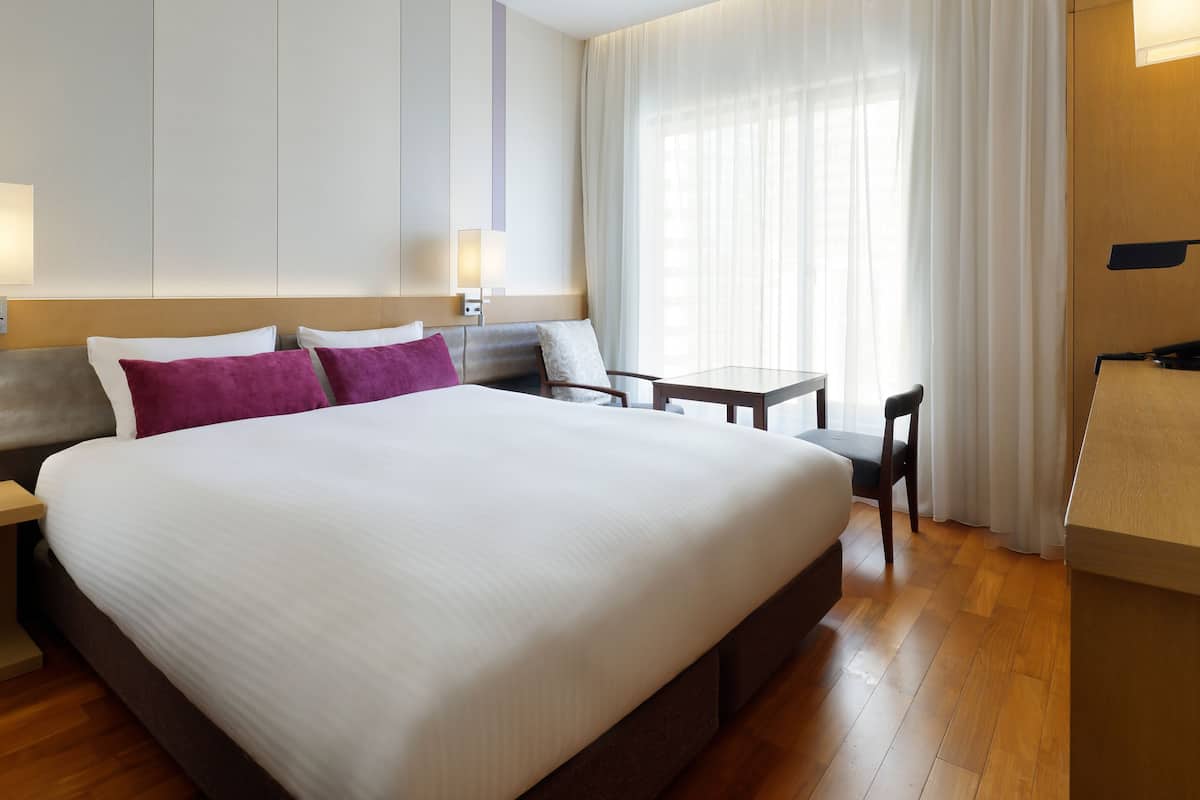 Une chambre d’hôtel avec un grand lit, un bureau et une chaise.