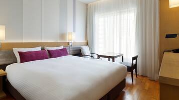 A hotel room with a large bed, a desk, and a chair.