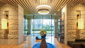 Een moderne lobby met een houten plafond, stenen muren en een centrale tafel met een bloemstuk.