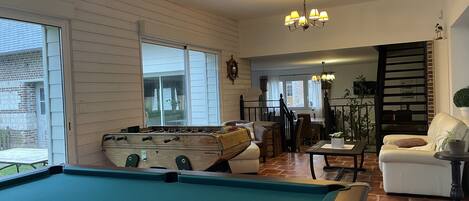A cozy living room with a pool table, a sofa, and a dining area.