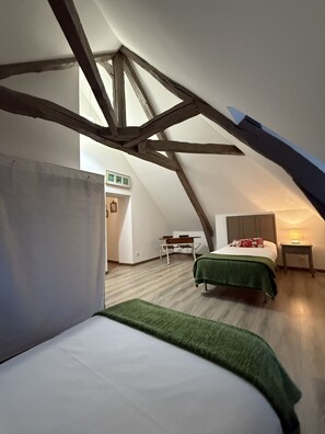 Cozy attic retreat with a large bed, desk, and lamp.