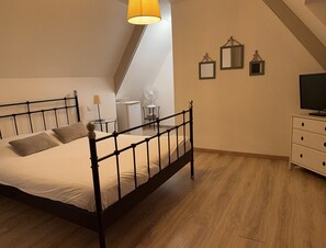 A bedroom with a bed, a desk, a chair, a lamp, a fan, and a TV. - Château de Grèges (Greges)