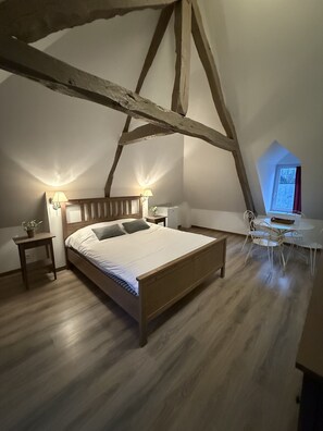 Relax in this serene bedroom with a comfortable bed, bedside tables, and a charming sloped ceiling.