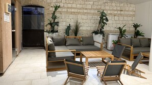 A modern living room with a stone wall, wooden furniture, and potted plants.