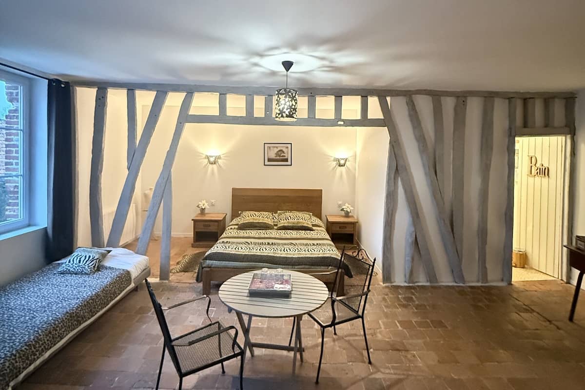 Una habitación acogedora con cama, una mesa redonda y sillas, una ventana y una puerta.