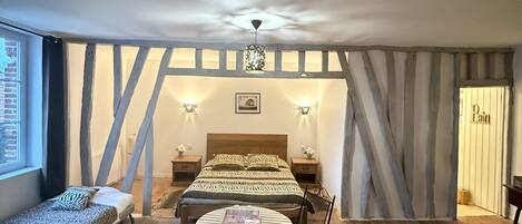 Una habitación acogedora con cama, una mesa redonda y sillas, una ventana y una puerta.