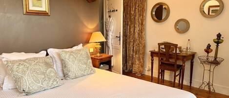 A hotel room with a bed, a table with chairs, a lamp, and a mirror on the wall.