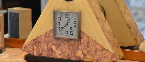 A clock with a marble base and a triangular top, placed on a marble countertop.