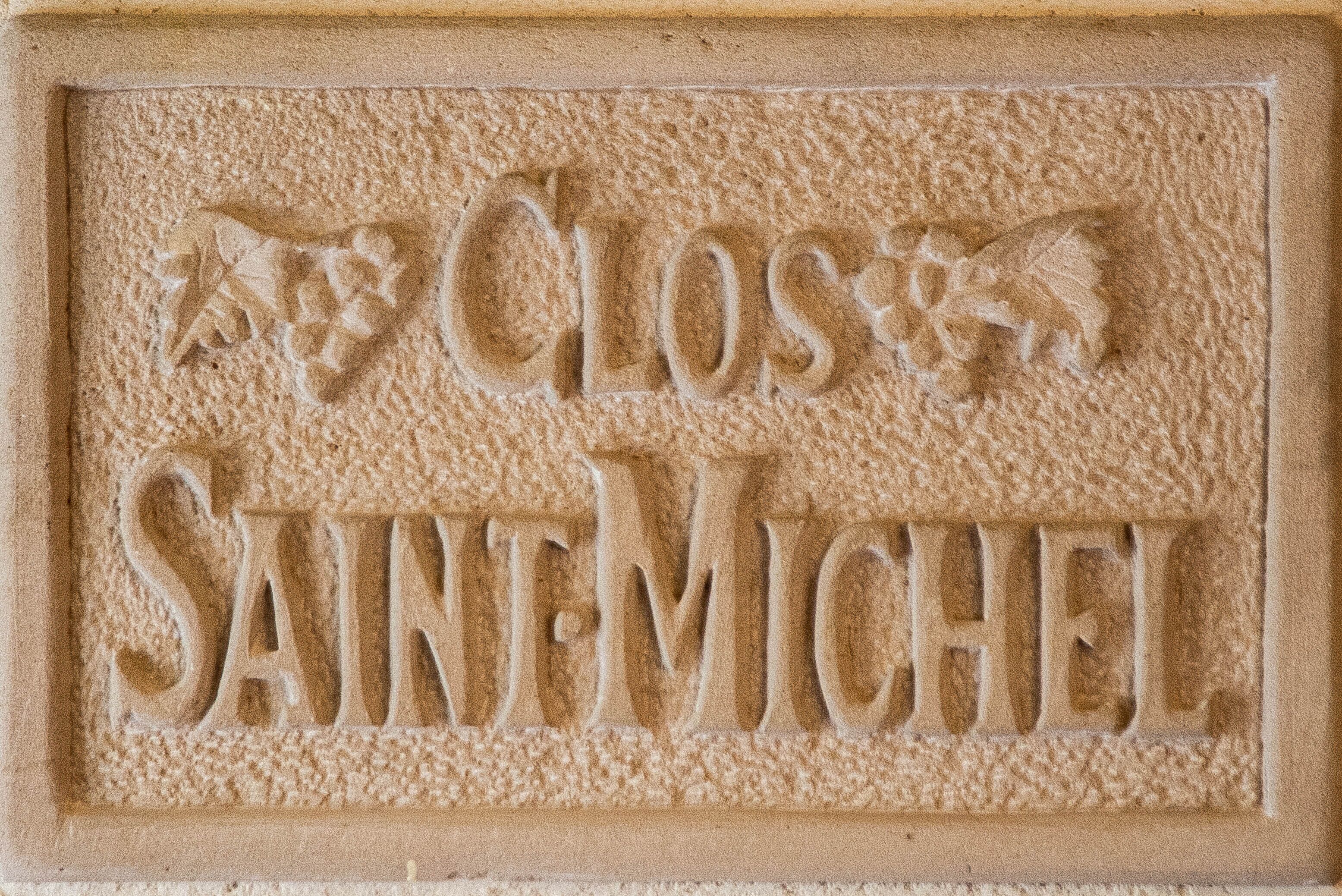 Un rilievo con le parole "CLOS" e "SAINT-MICHEL" su una superficie strutturata.