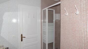 Un bagno con una porta bianca, pareti piastrellate e una zona doccia.