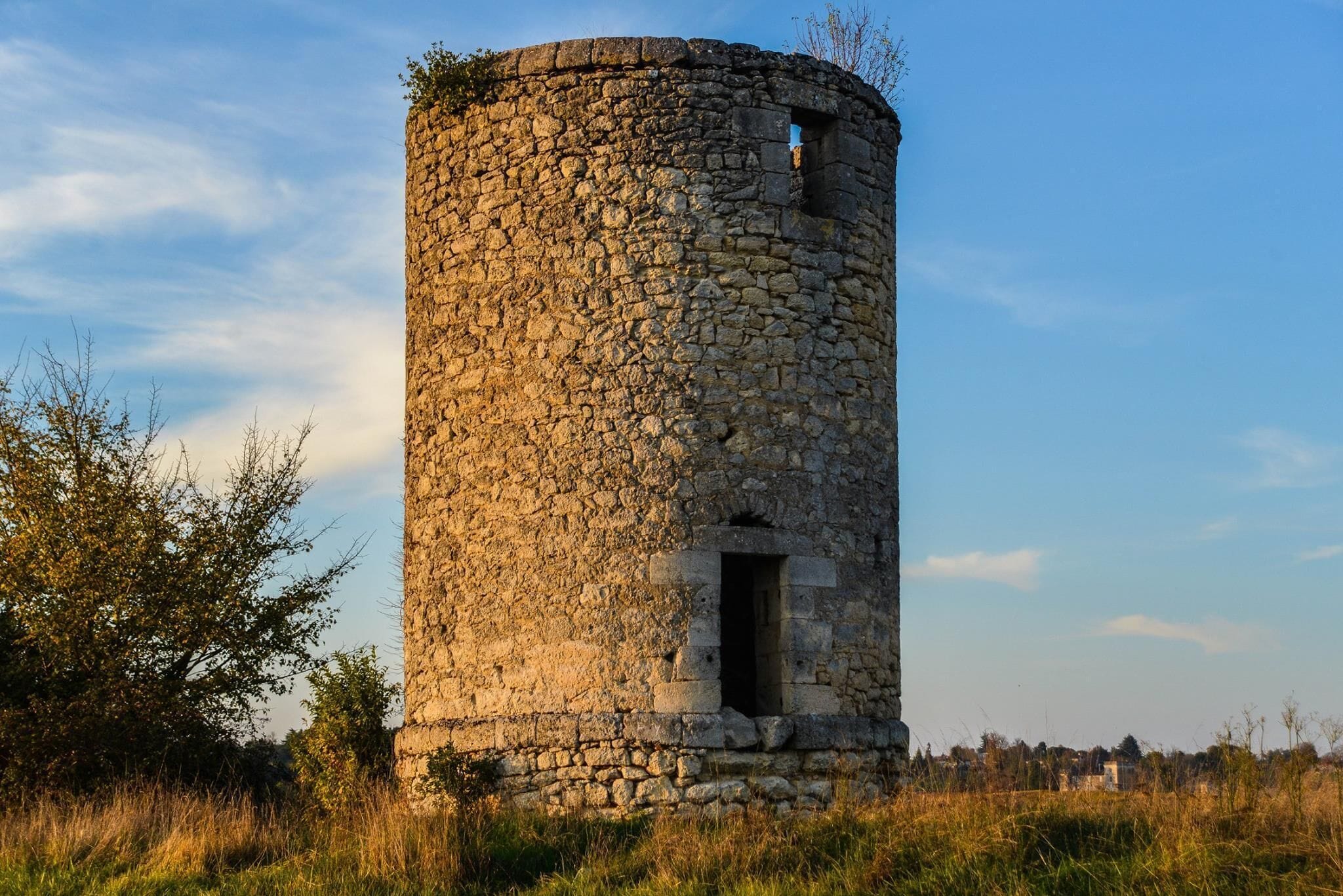 A stone tower with a circular base and a small window near the top.