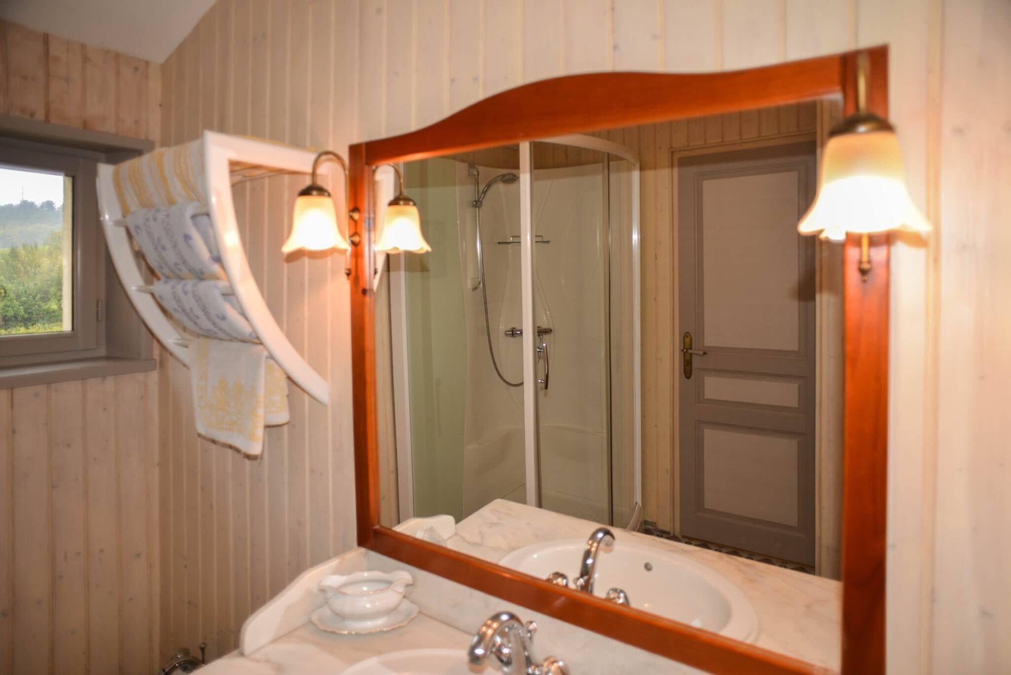 A bathroom with a large mirror, two sinks, and a shower.