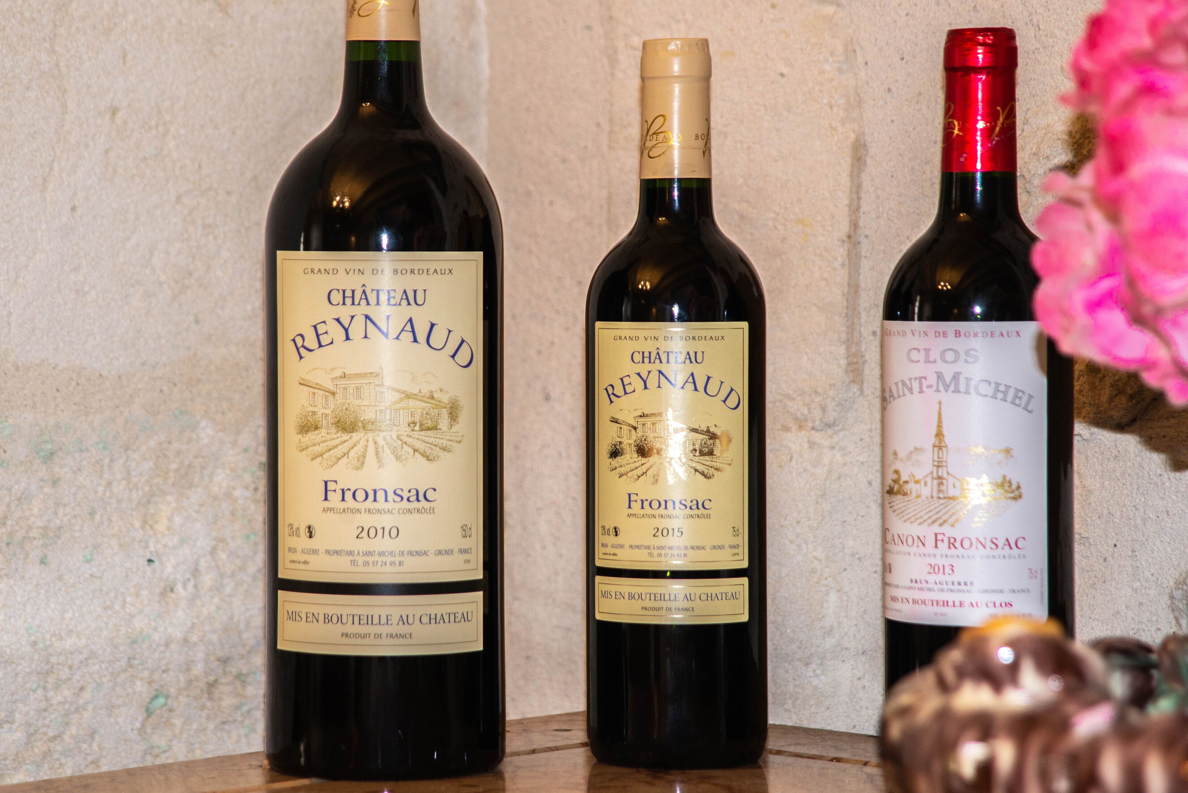 Three bottles of Chateau Reynaud wine on a shelf.