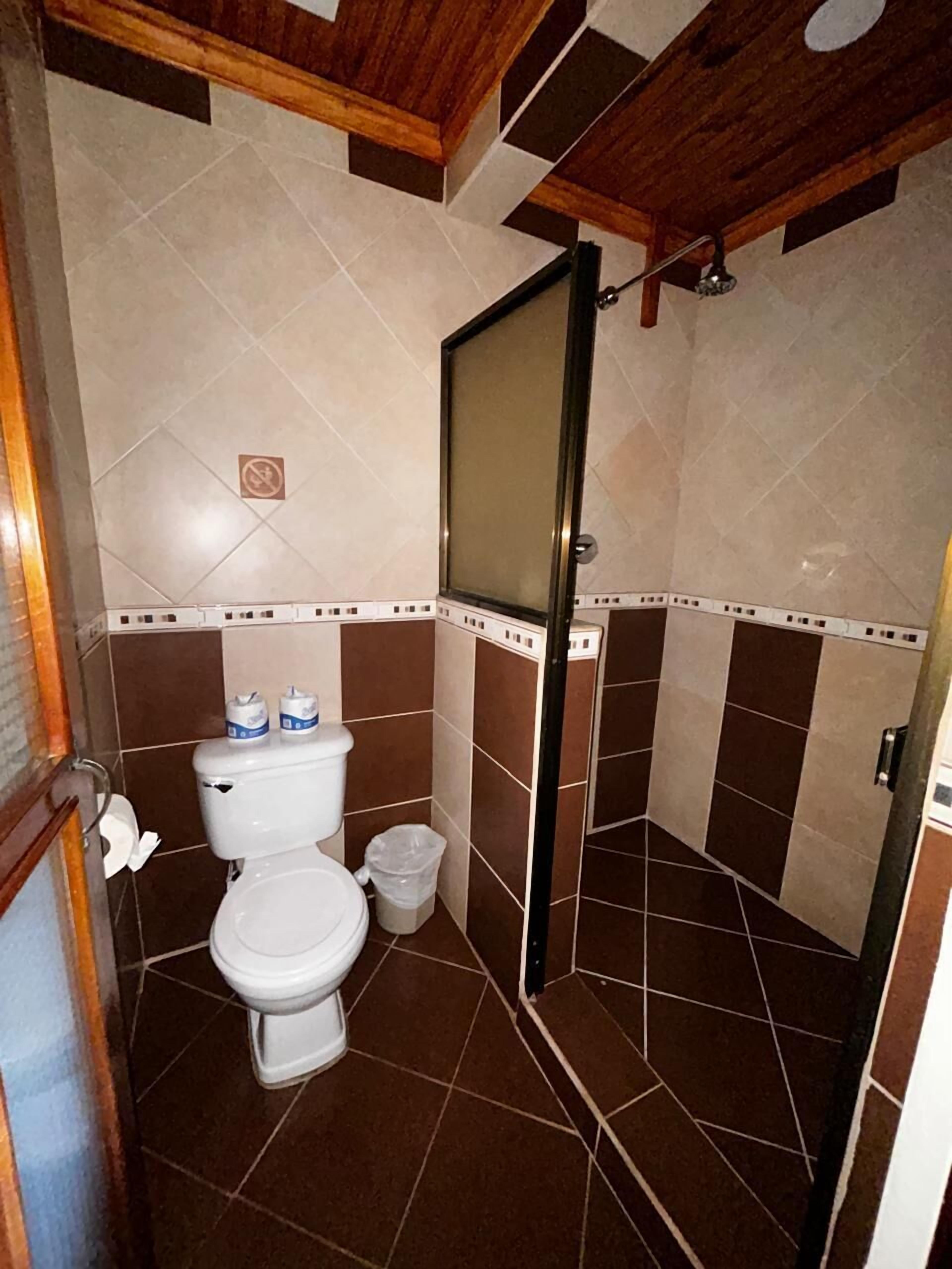 A bathroom with a toilet, a shower, and a tiled floor.