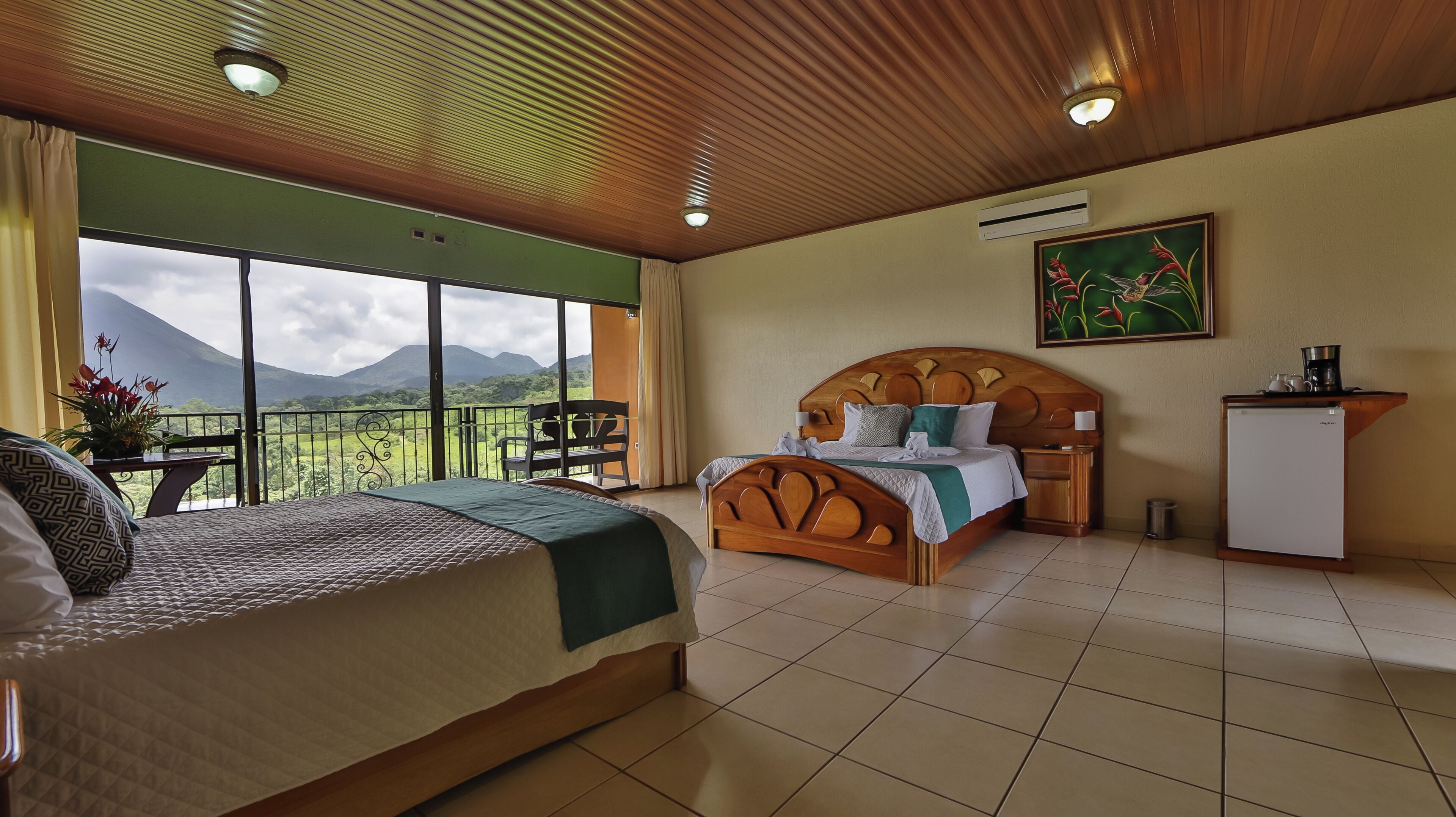 Habitación de hotel con una cama grande, un escritorio, una silla y vistas a las montañas.