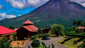 A building with a red roof and a small car parked in front. - Hotel Linda Vista (La Fortuna)