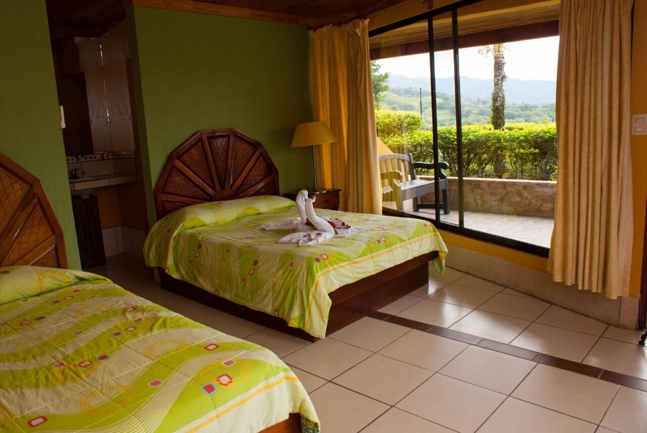 A hotel room with two beds, a view of the outdoors, and a wooden headboard.