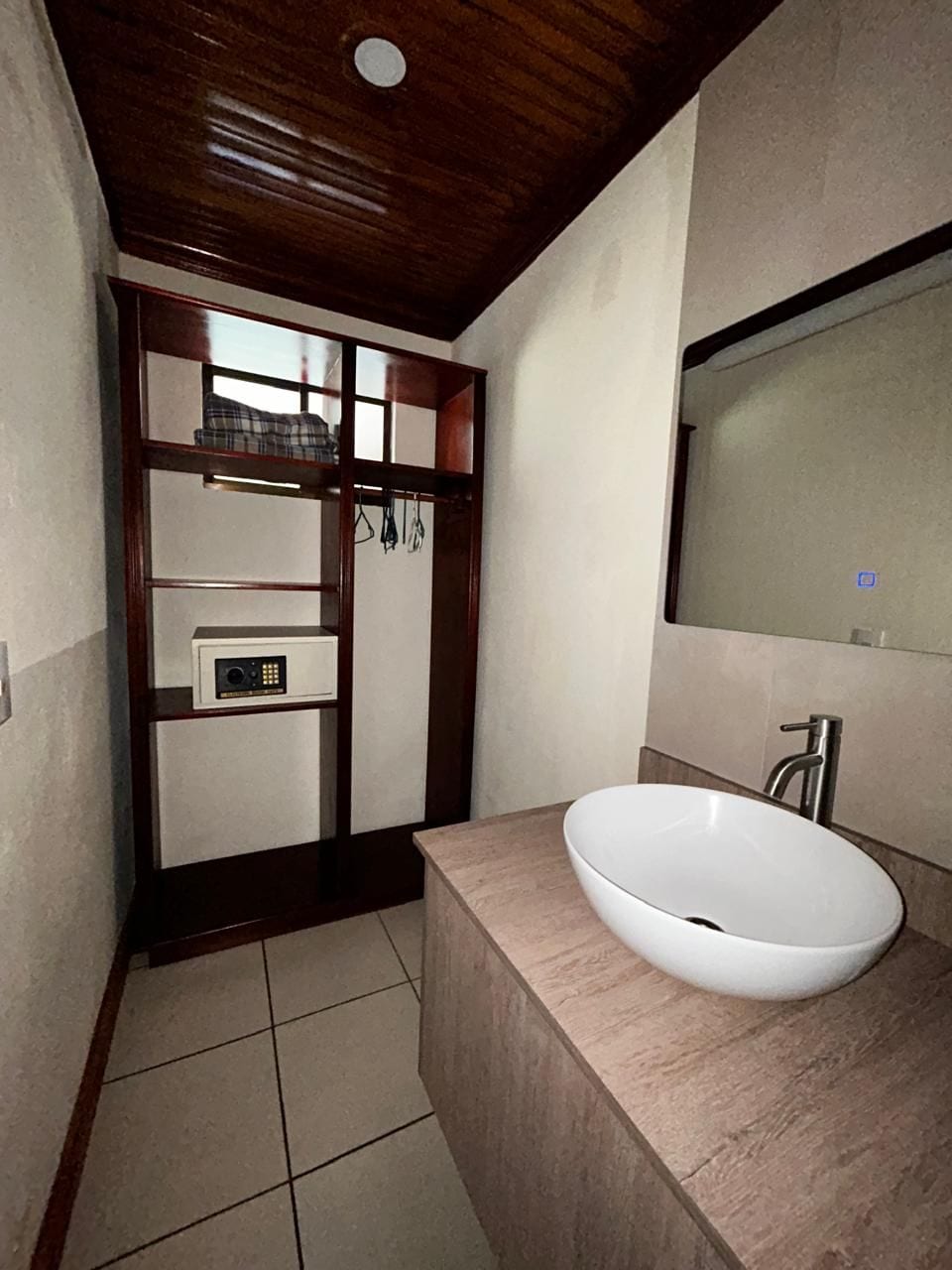 A bathroom with a wooden ceiling, a white sink, and a mirror above it.