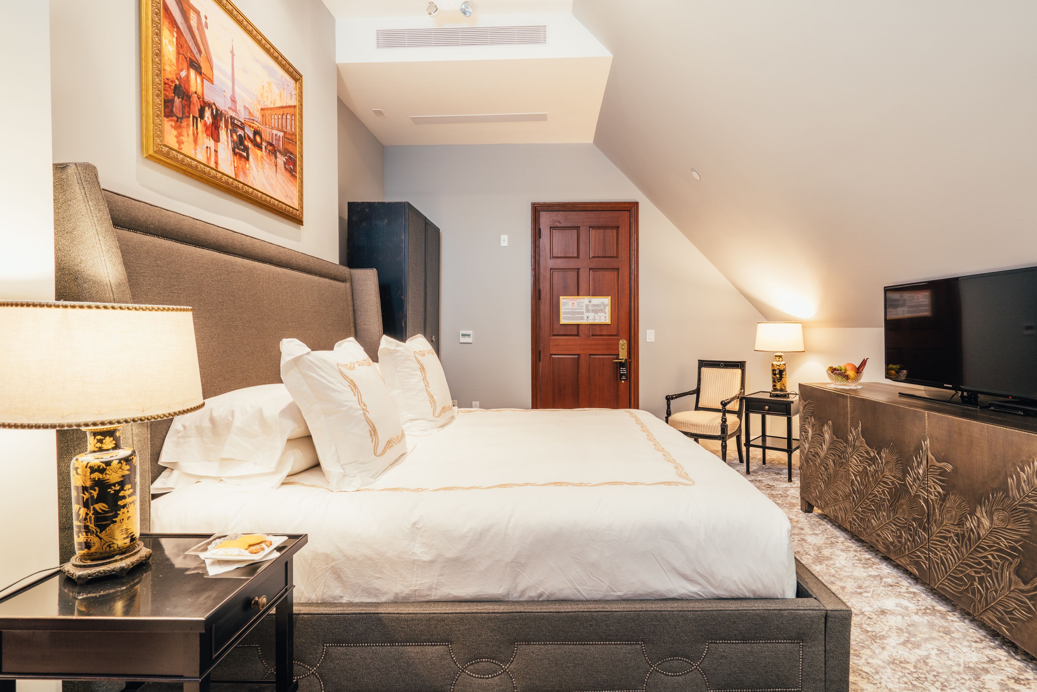 Une chambre d’hôtel avec un grand lit, une télévision, un bureau avec une lampe et un tableau au mur.
