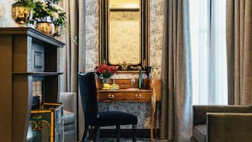 A room with a wooden desk, a chair, a mirror, and a window with curtains.