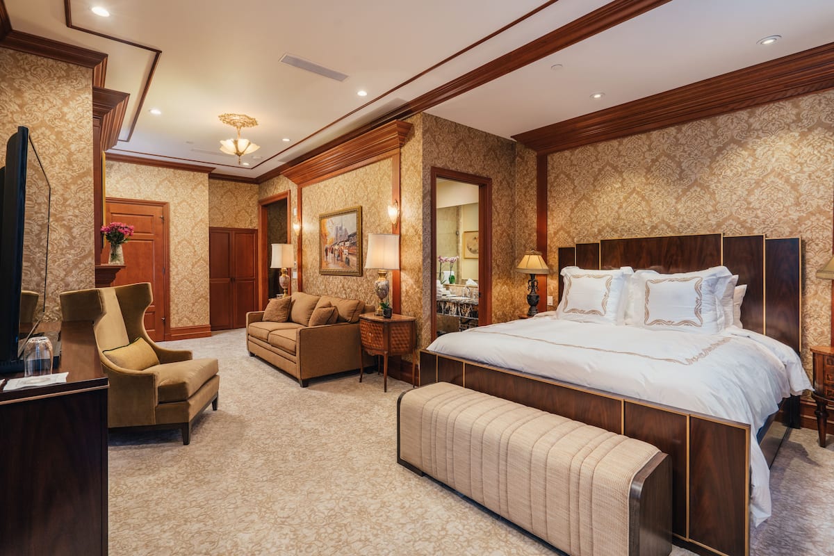 A hotel room with a large bed, a sofa, a desk, and a TV.